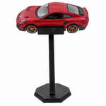 A red die-cast model sports car displayed on a black stand against a plain white background.