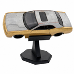A diecast model car in a two-tone silver and gold finish, displayed on a black plastic stand against a white background.